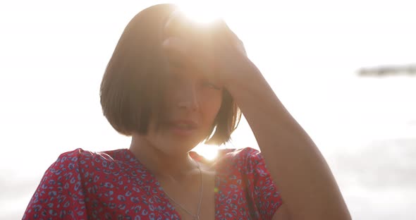 Charming Brunette Woman Touching Hair at the Sea Sunset