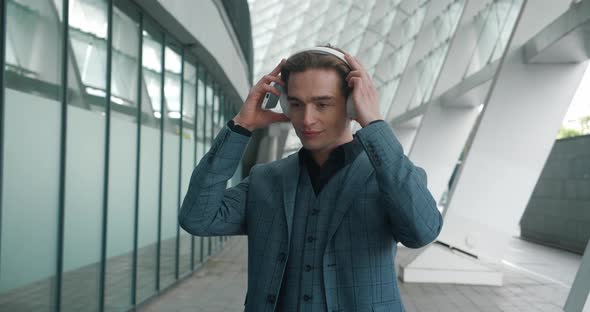 Smiling Relaxed Businessman Puts on Wireless Headphones for Listening Music alt