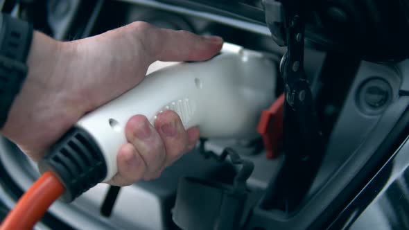 Male Hand Is Removing an Electrical Fuel Nozzle alt