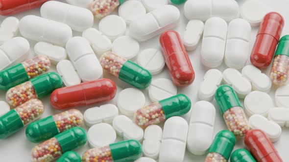 Different Types of Medical Pills and Capsules Rotating on White Surface