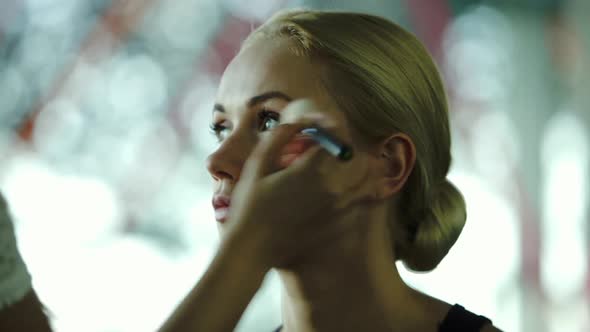 Makeup artist applying blush on womens face