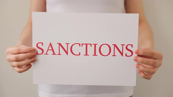 Close Up of a Protester Hands Holding Cardboard Banner with the Words Sanctions alt