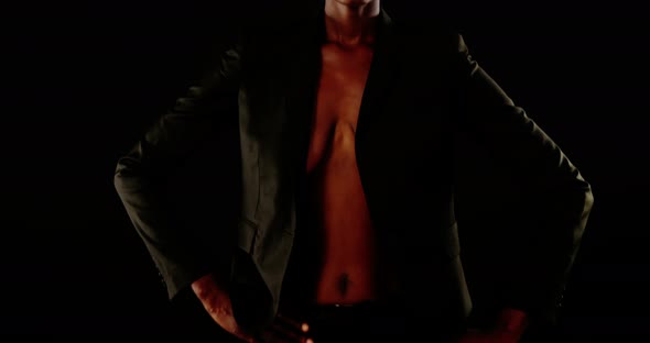 Androgynous man in blazer posing against black background alt