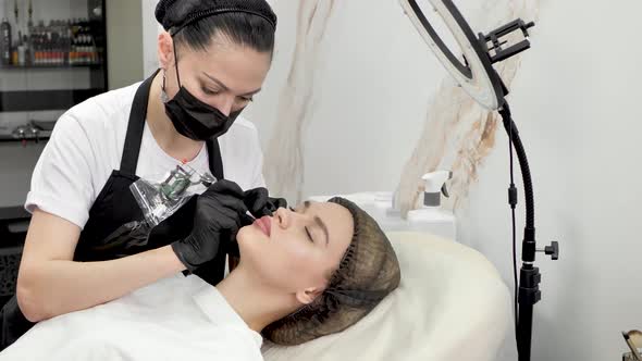 A Cosmetologist Applies Permanent Makeup to the Lips in a Beauty Salon alt