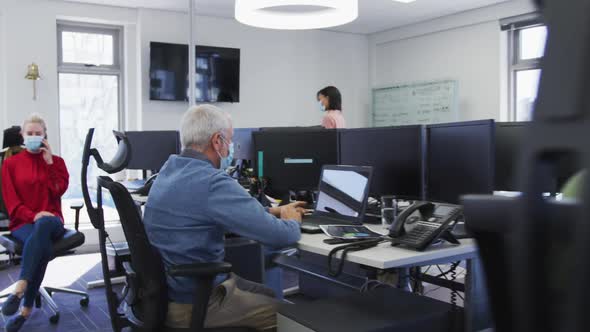 Man wearing face mask using digital tablet at office alt