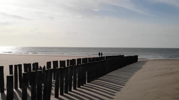 Couple walking on the beach in autumn or winter. Horizon and sea. Dolly shot alt