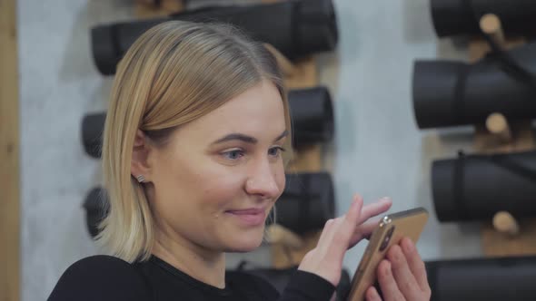 Close-up of A Blonde Athletic Woman in a Black Top and Leggings Watching A Workout Program alt
