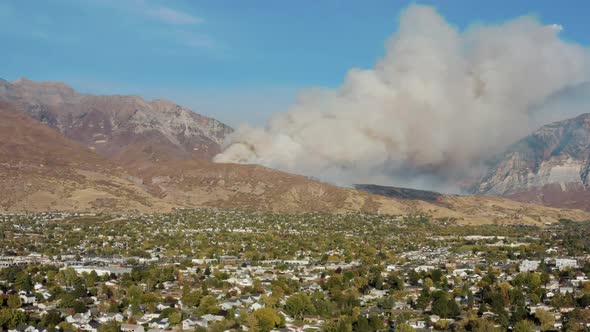 Aerial shot of DC-10 dumping fire retardant on wildfire on mountain above city from a safe distance, alt