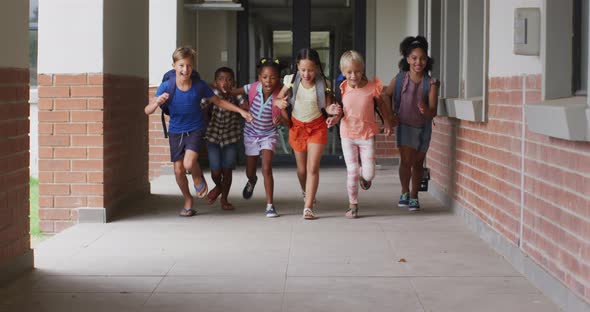 Video of happy diverse pupils running on school corridor alt