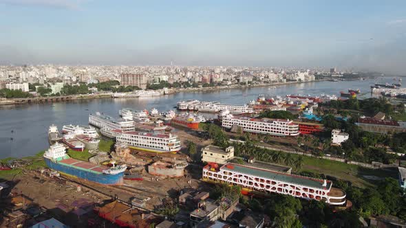 Aerial: dockyard at Buriganga river bank with city landscape in Dhaka, Bangladesh - drone establishi alt