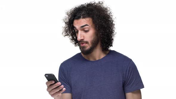 Portrait of Brazilian Guy with Curly Hair in Casual Dark Blue Tshirt Browsing Internet on Smartphone alt