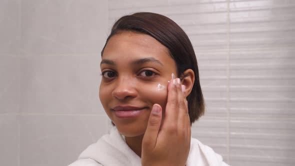 Closeup of a Young Woman Face Using a Moisturizing and Nourishing Cream