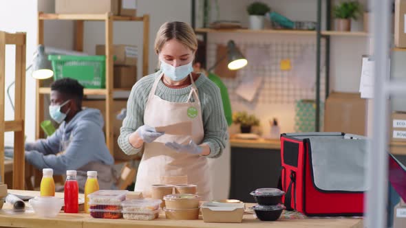 Young Woman in Mask Packing Order at Healthy Food Delivery Service alt