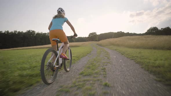 Woman Cycling on Electric Mountain Bike Summer Sunset Rural Landscape