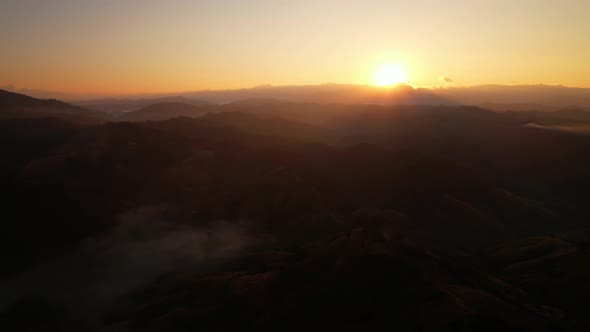4K Aerial view from drone over mountains fog. Golden scenery at sunrise alt