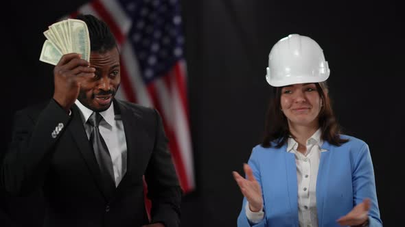 African American Male Politician Passing Cash Money to Caucasian Woman in Hard Hat in Camera Flashes alt