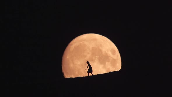 Silhouette of Dancing Woman Against Big Moon at Night