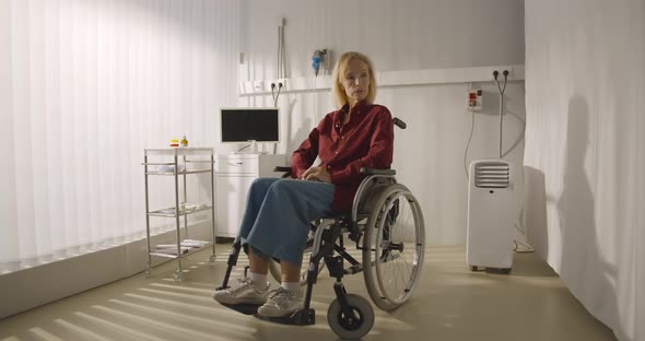 Pensive Disabled Elderly Patient Sit on Wheelchair Alone in Hospital Room alt