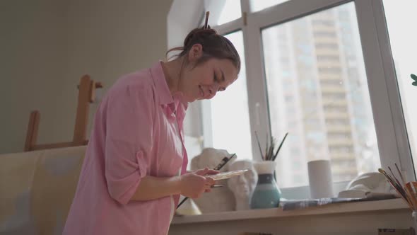 Caucasian Woman Artist Working on a Painting in Bright Daylight Studio alt