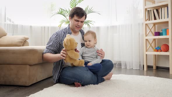 Baby boy with father having fun and playing with teddy bear alt