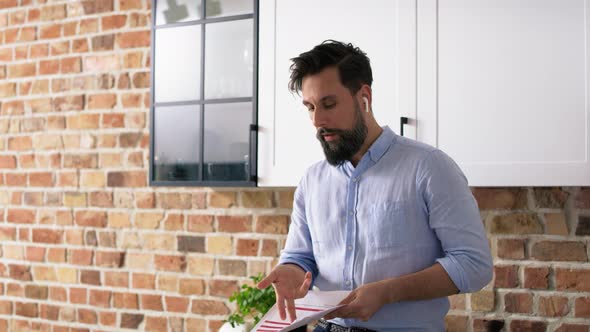 Tracking video of man with headphones refusing documents at home. Shot with RED helium camera in 8K. alt