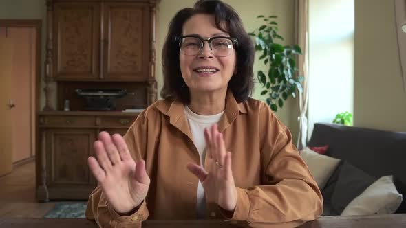 Businesswoman Talking and Gesturing in Front of Screen Sitting at Table in Apartment Room alt