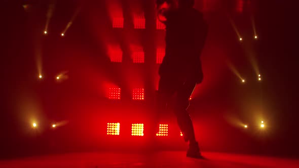 Silhouette of a Talented Young Hip Hop Dancer. Hip Hop Street Dance on a Stage in Dark Studio with alt
