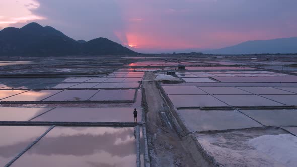Rising aerial view of tourists exploring vast endless salt fields during golden hour in Phan Rang, V alt
