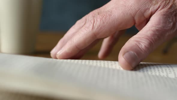 Hand of Senior Man Touching Page of Book alt
