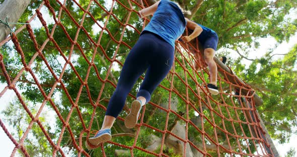Fit people climbing a net during obstacle course 4k alt
