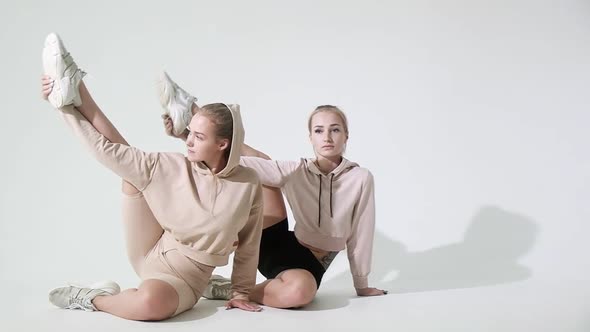 Group yoga aerobics classes on white background. Girls sit on floor stretch legs alt