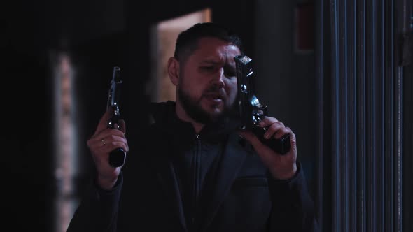 Dangerous Man Looking Over His Guns and Starts Shooting to a Camera alt