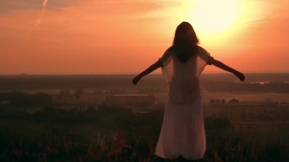 Back View Woman Standing on the Field with Green Grass in the Early Morning alt