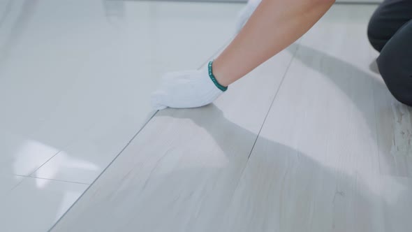 Close-up of Craftsman worker work by installs laminate board on corridor floor to renovate house. alt