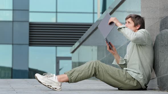 Young Male Journalist Freelancer Sitting Outdoors Using Laptop Typing on Keyboard of Electronic alt