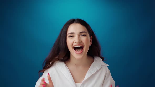 Surprised Young Woman Celebrating Success Against Blue Background