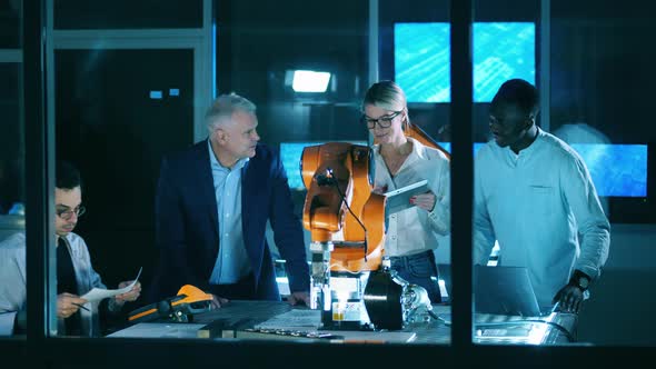 International Group of Scientists Observing a Robotic Arm in a Modern Laboratory alt