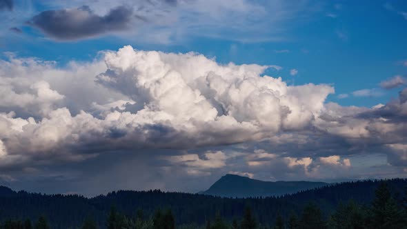 Big cumulus cloudsover forest landscap. A rainbow is being formed 4K alt