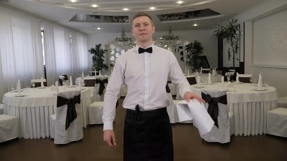 Portrait of a Waiter in a Restaurant Against the Background of Served Tables alt