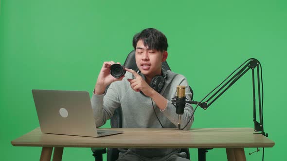 Asian Man With Headphone And Computer Reviewing Camera Len On Green Screen Background alt