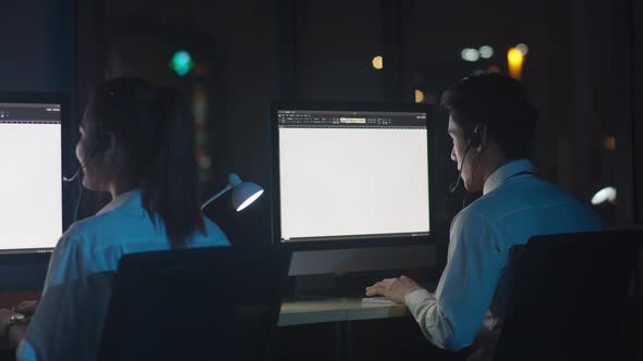 Call center team using computer and microphone headset working technical support in night office alt
