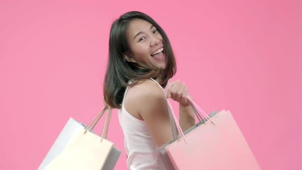 Young fashionable Asian woman holding shopping bags feeling adorable glad woman rejoices success. alt
