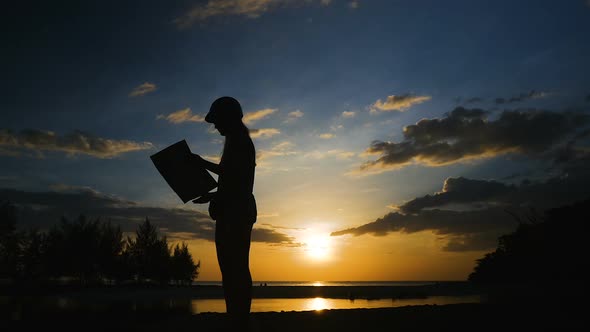 Silhouette Female Traveler at Sunset. The Girl Looks at the Map and Looking for a Path on a