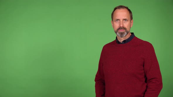 A Middleaged Handsome Caucasian Man Presents Something to the Camera with a Smile  Green Screen