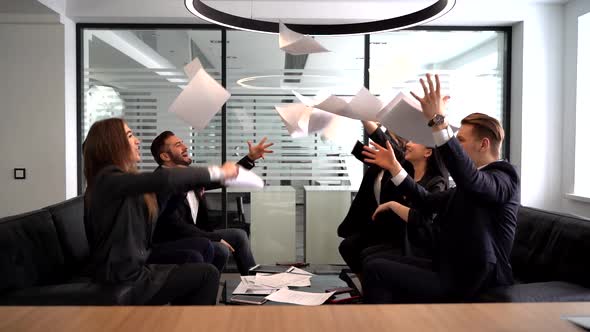 Group of Business People Rejoicing in Closing the Quarter Successfully Tossing Up Paper Documents in