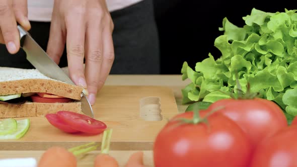 Woman's hands cuts club healthy sandwich in a half by kitchen knife