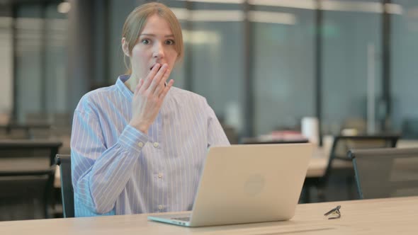 Young Woman Feeling Shocked While Using Laptop in Office alt