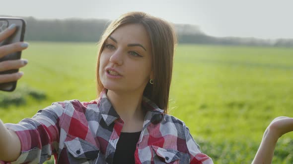 Young Woman Agricultural Blogger Shows a Green Field of Wheat Live alt