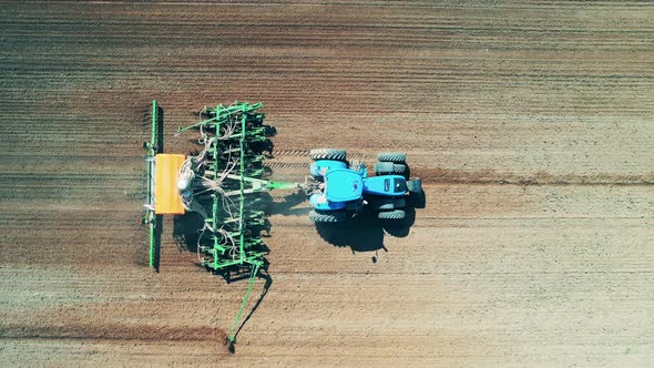 Sowing Tractor Riding Along the Field in a View From Above alt