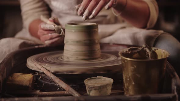 Young Woman Potter Cutting Off the Excess Out of Clay Pot on the Wheel alt